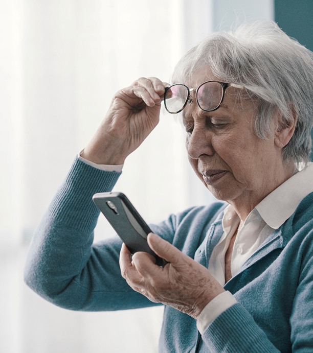 Woman lifting up her glasses and squinting at phone