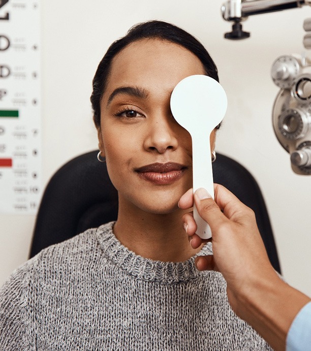 Woman in sweater having eye covered for eye exam