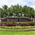 Outdoor stone sign by green trees that reads Waterside Estates