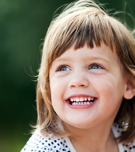 Little girl smiling outside with hair blowing in the wind