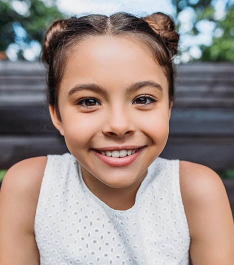 Smiling little girl sitting on park bench