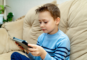 Little boy staring at tablet on couch